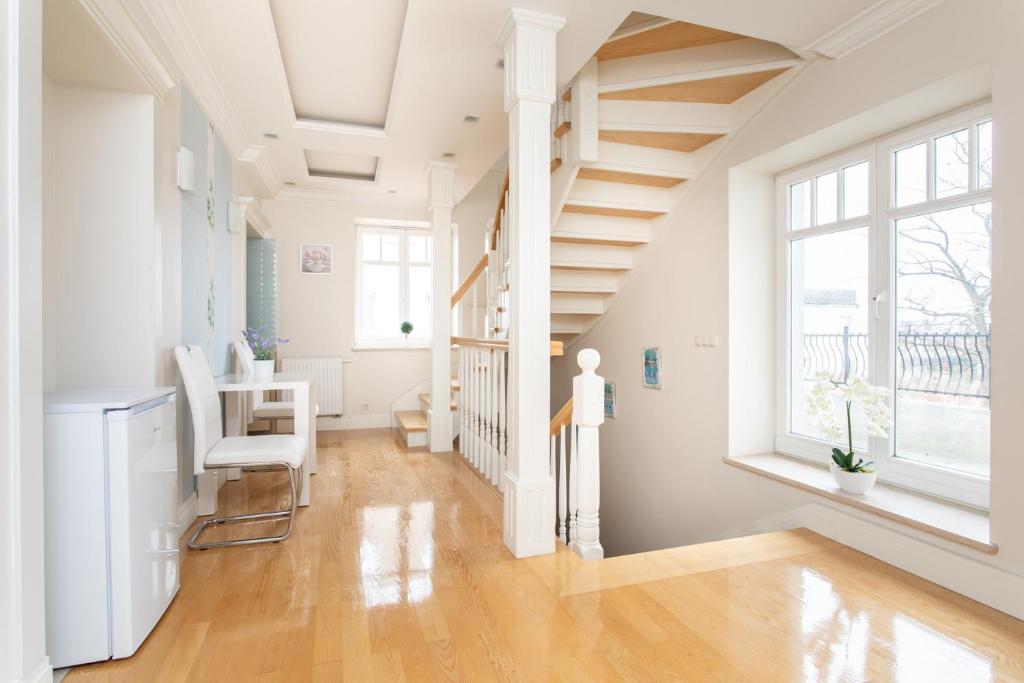 ソポトにあるroomsy guest houseの階段、テーブル、椅子が備わる白い部屋