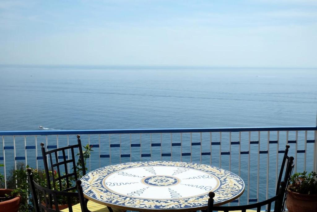 ein Tisch und Stühle auf einem Balkon mit Blick auf den Ozean in der Unterkunft MAGICA VISTA in Amalfi