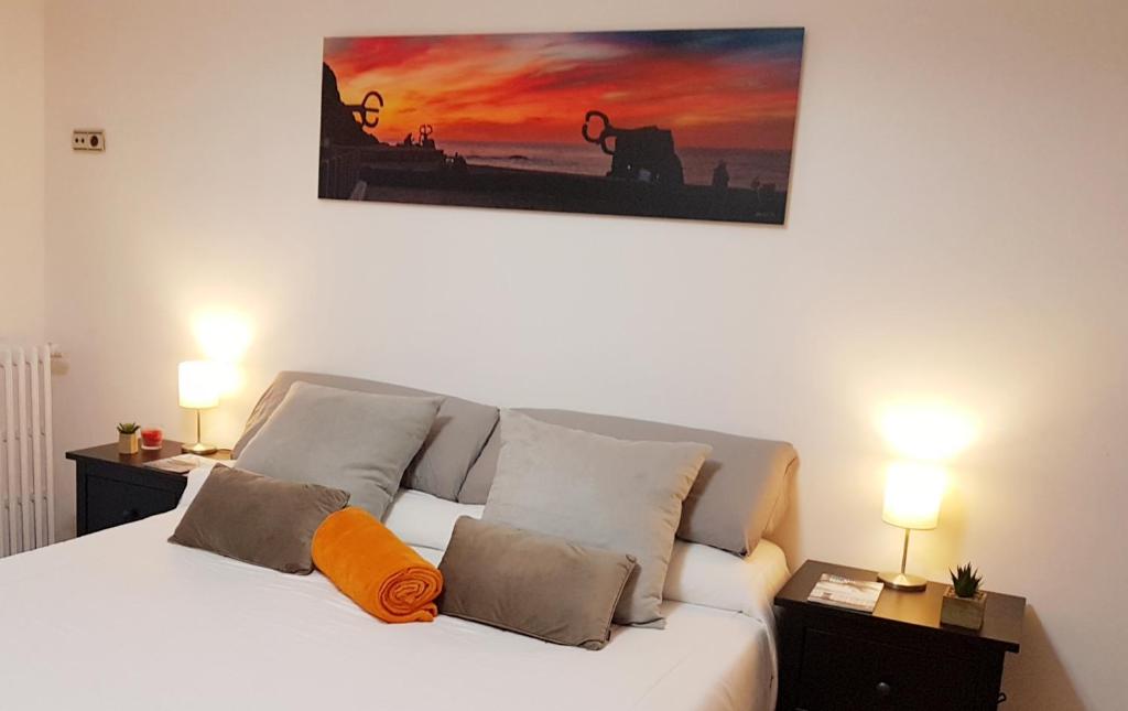 ein Schlafzimmer mit einem weißen Bett und einem orangefarbenen Kissen in der Unterkunft URBIETA CENTRO in San Sebastián