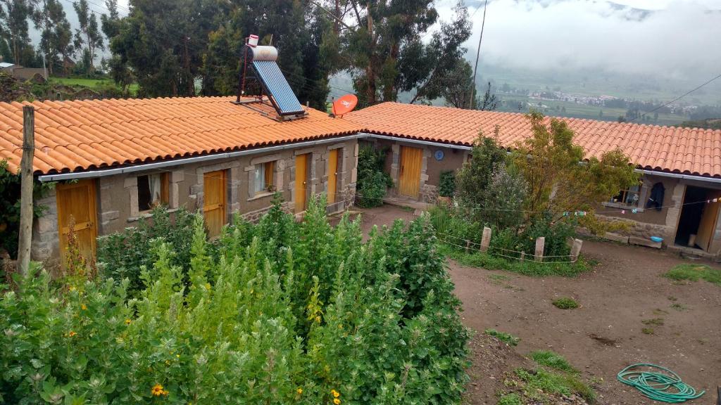 una casa con techo naranja y jardín en Casa vivencial Yuraq Qaqa, en Coporaque