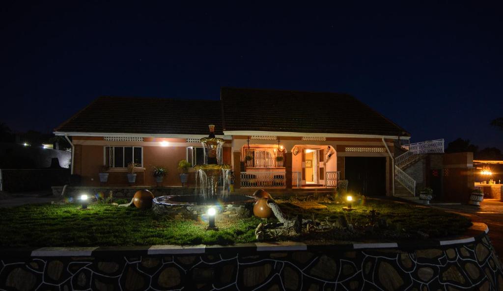 uma casa com uma fonte em frente à noite em Lake Victoria Country Home em Entebbe