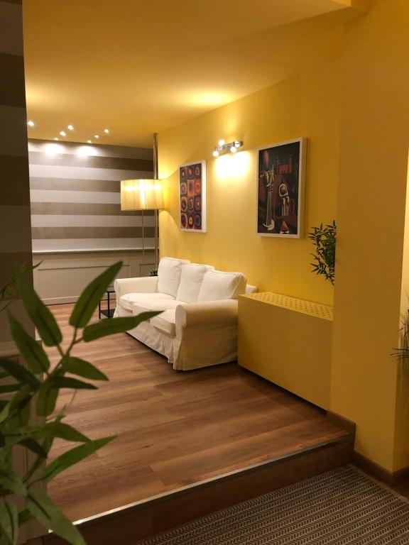 una sala de estar con sofás blancos y una planta en Apartment Hotel Marchesini, en Rávena
