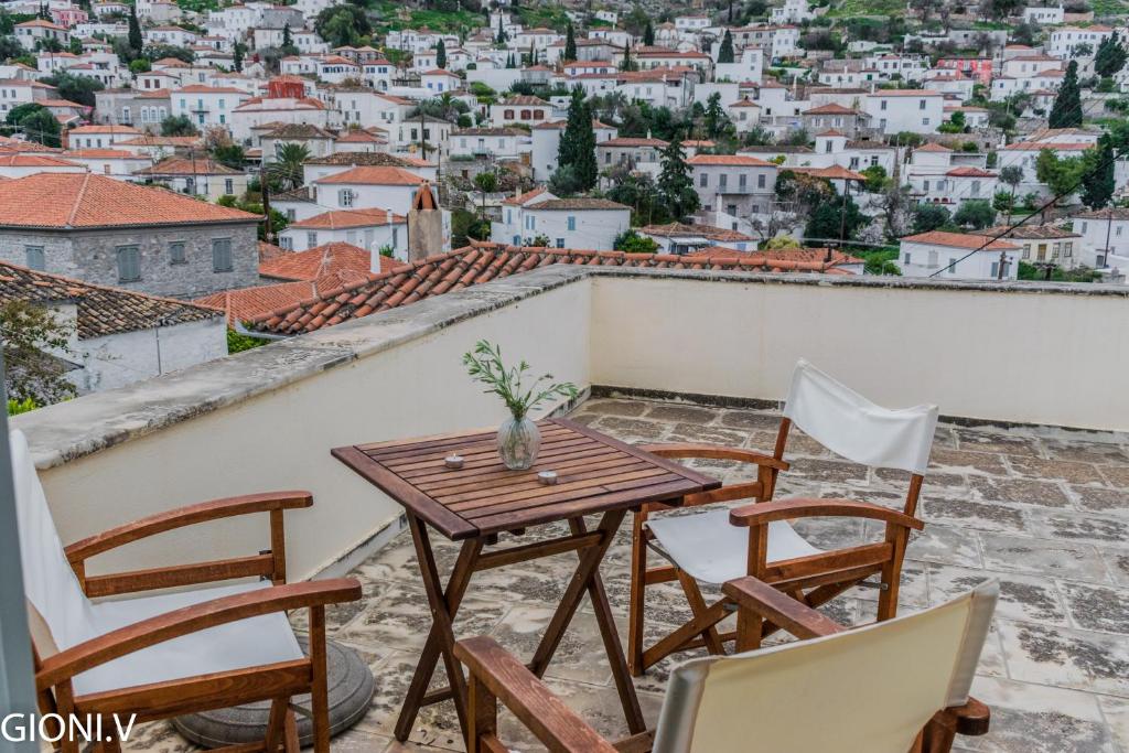 uma mesa e cadeiras numa varanda com vista para a cidade em Angeliko's Vourgaris stone house em Hydra