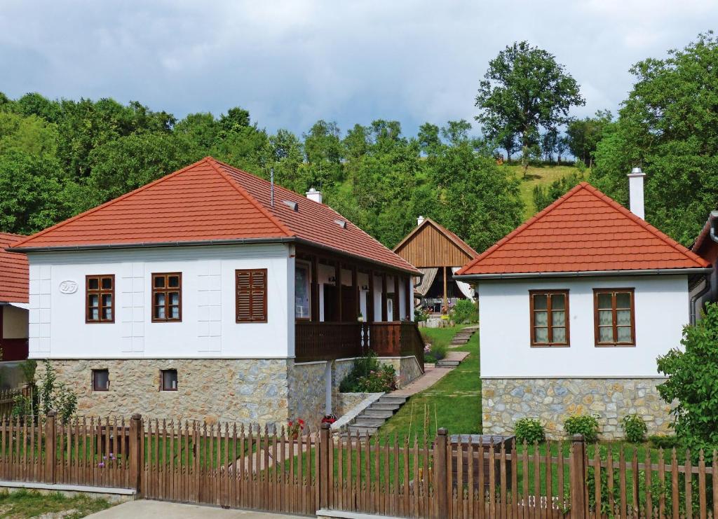 une maison avec des toits rouges et une clôture dans l'établissement Fruktárium vendégház, à Trizs