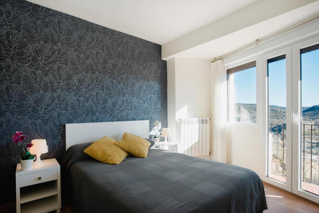 a bedroom with a bed and a wall of windows at Hotel El Cid in Morella