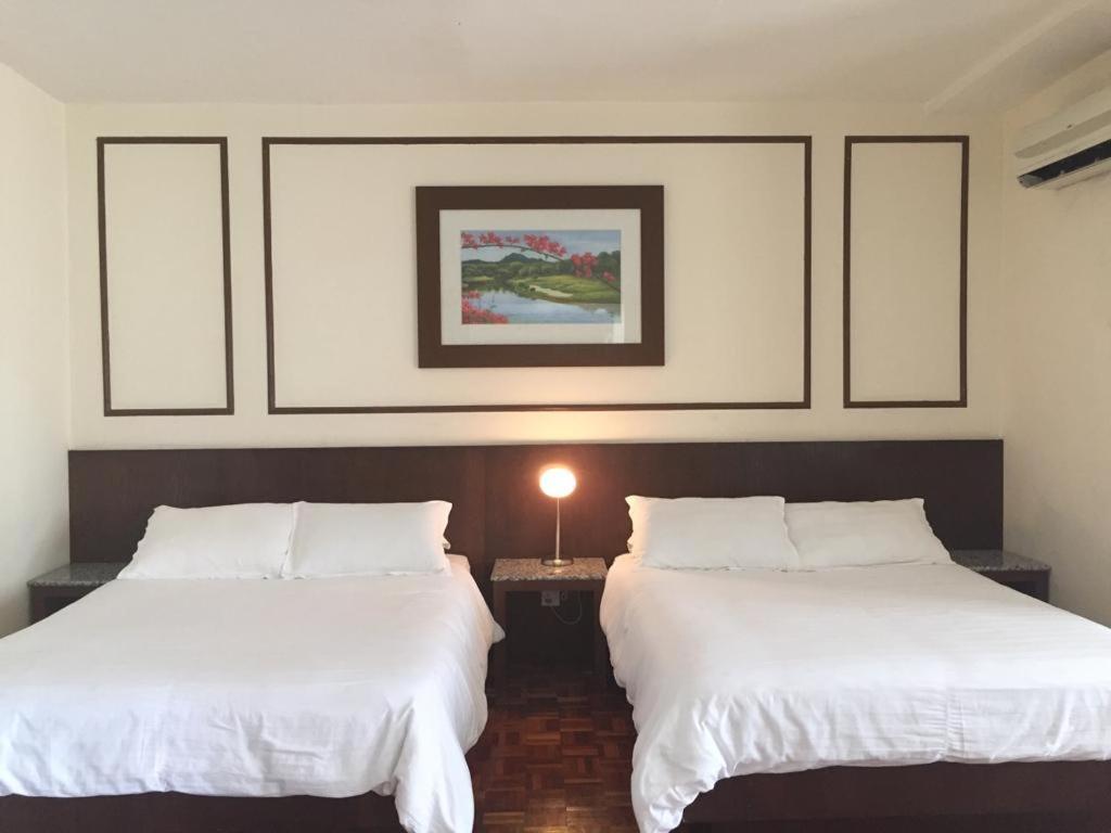 two beds in a hotel room with white sheets at D savoy @ Famosa by MR in Melaka