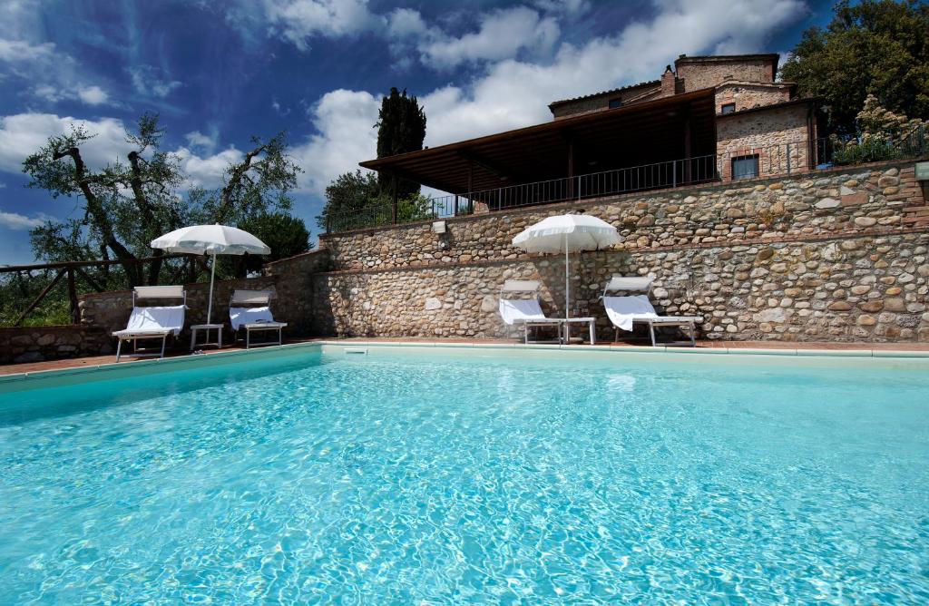 a swimming pool with two chairs and umbrellas at Agriturismo Poggio Bonelli in Castelnuovo Berardenga