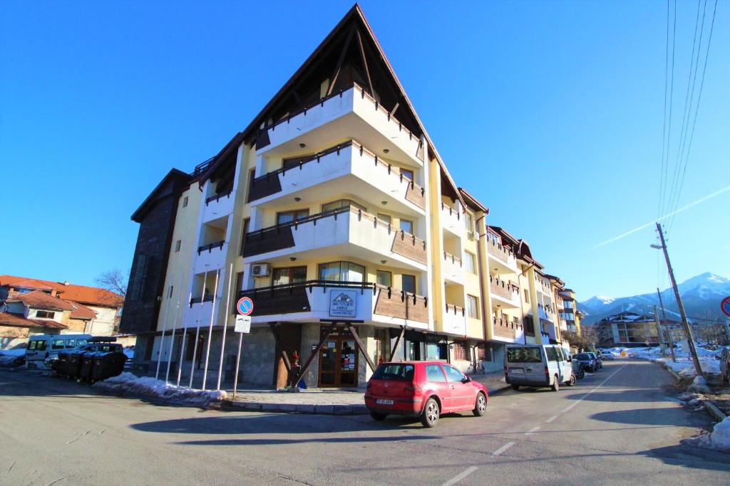 um edifício com um carro vermelho estacionado em frente dele em Mountview Lodge Apartments em Bansko