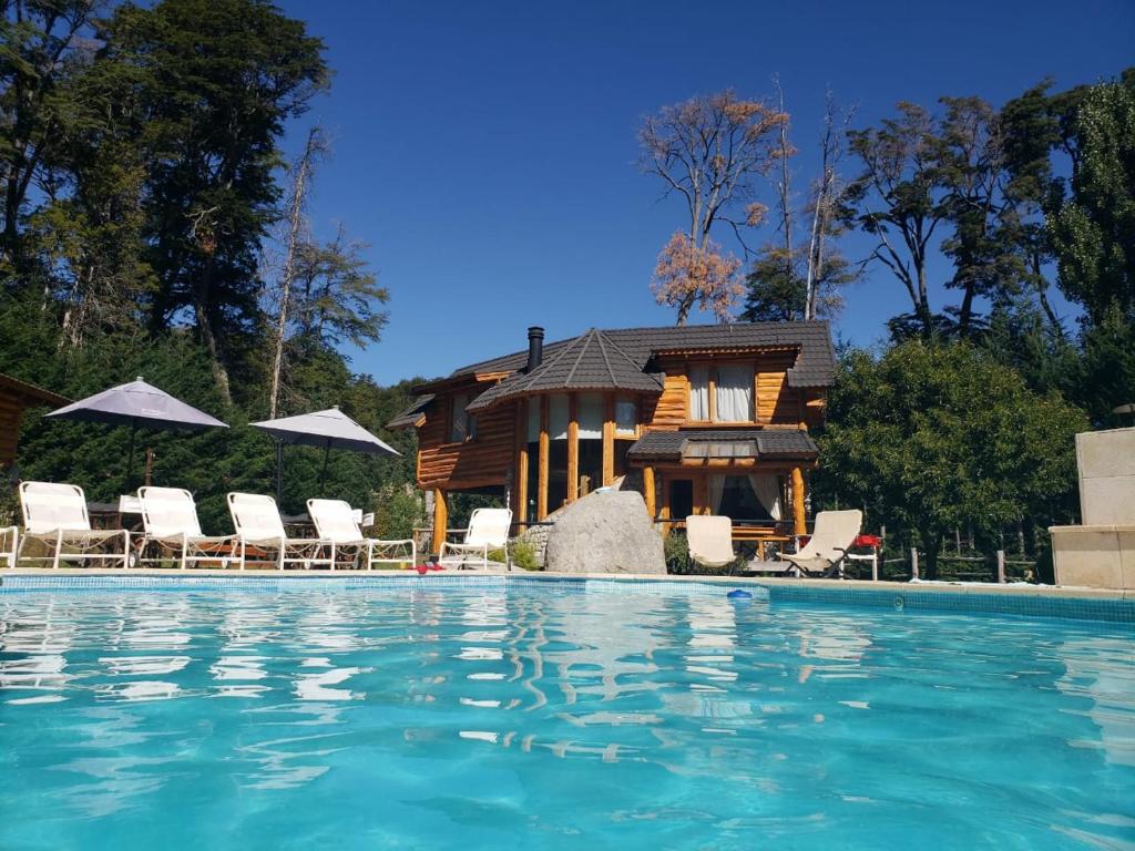 una casa con piscina frente a una casa en El Raulí del Bonito en Villa La Angostura