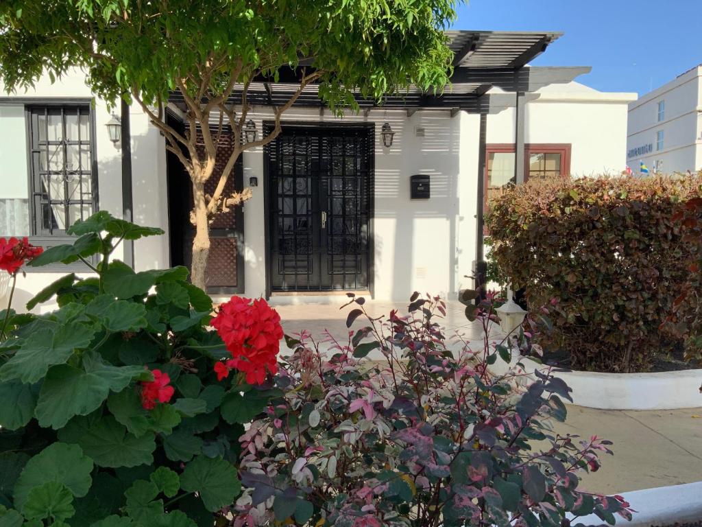 uma casa branca com uma porta preta e flores vermelhas em Villa Oasis em Puerto del Carmen
