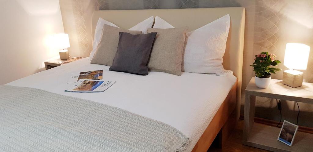 Un dormitorio con una cama blanca con almohadas y un libro. en Rooms Velo, en Korenica