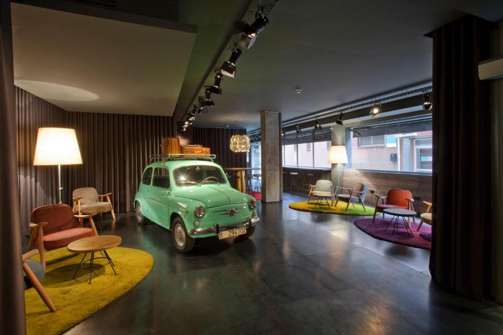 een oud groen busje in een kamer met stoelen en tafels bij Sixties Ramblas in Barcelona