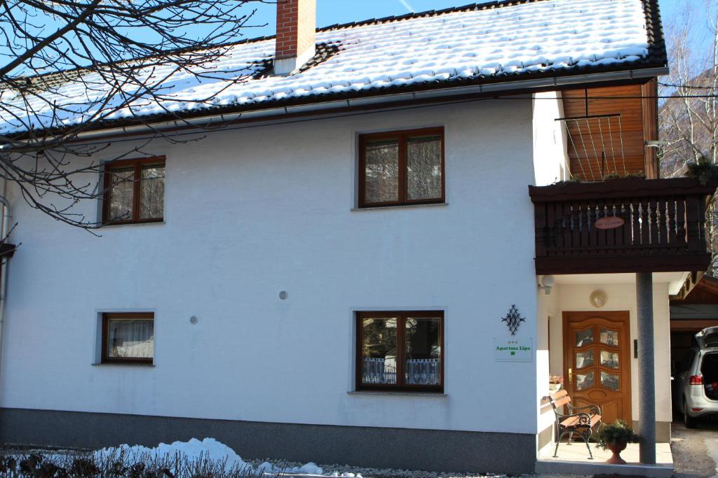 a white house with snow on the roof at Apartma Lipa in Mojstrana