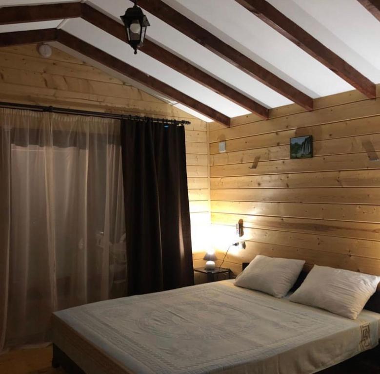 a bedroom with a bed with a wooden wall at MiMi in Tsandrypsh