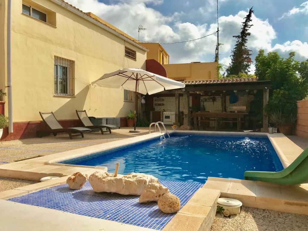 einen Pool im Garten mit Sonnenschirm in der Unterkunft Casa Rural LOS CORTESES in Los Díaz