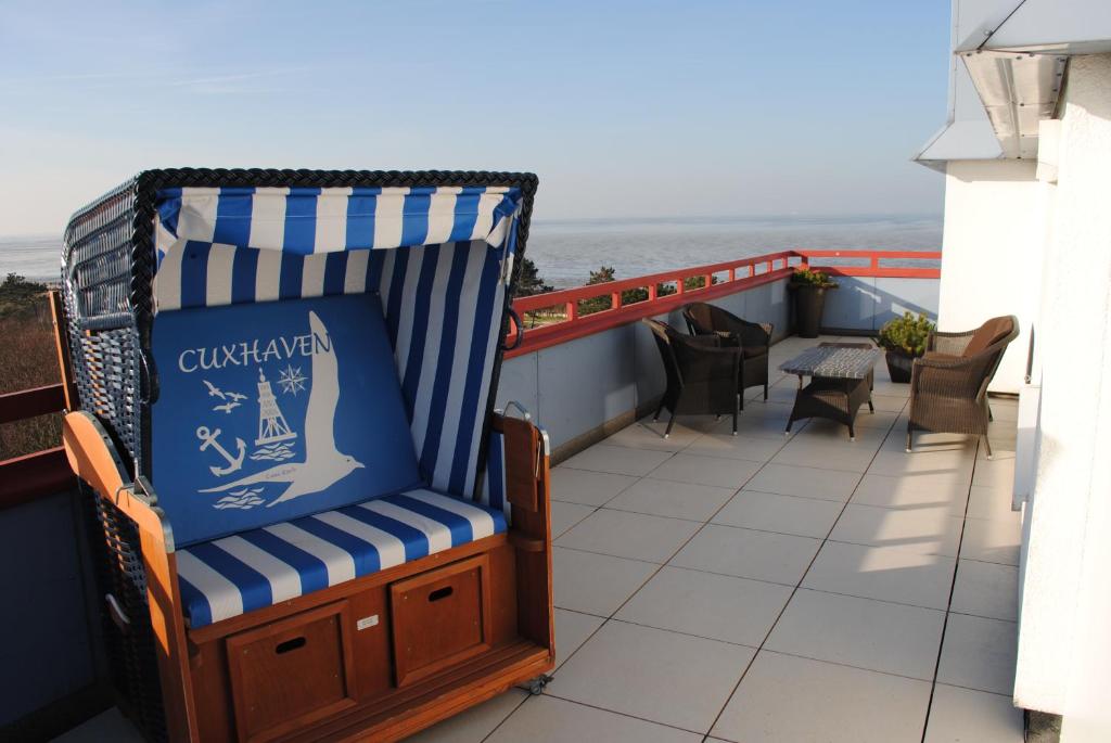 a rocking chair on a balcony with a view of the ocean at Terrassenhaus Penthouse-Wohnung 93 in Cuxhaven