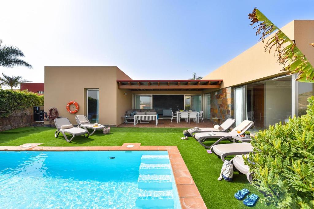 un patio trasero con piscina y una casa en Salobre Villa with Pool Par 4 nr 9, en Salobre
