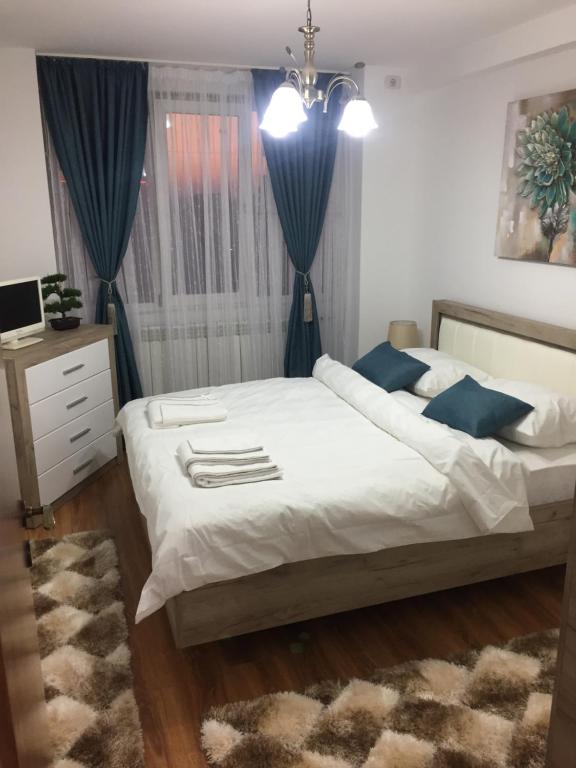 a bedroom with a bed with blue curtains and a rug at Roby apartament in Bucharest