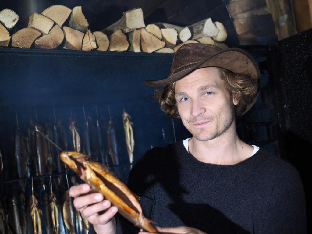 a man in a hat holding a bagel at Erlachmühle in Mondsee