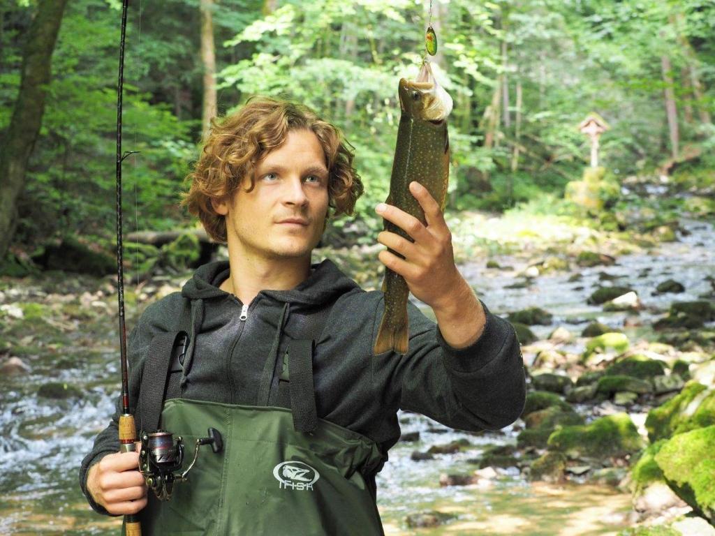 a man holding a fish on a rod in the woods at Erlachmühle in Mondsee