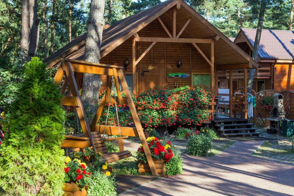 a wooden cabin with flowers in front of it at SOLEI in Pobierowo