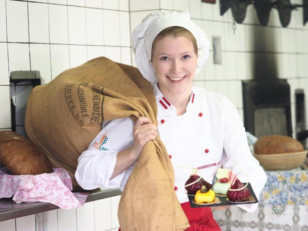 a woman in a kitchen holding a bag of bread at Erlachmühle in Mondsee