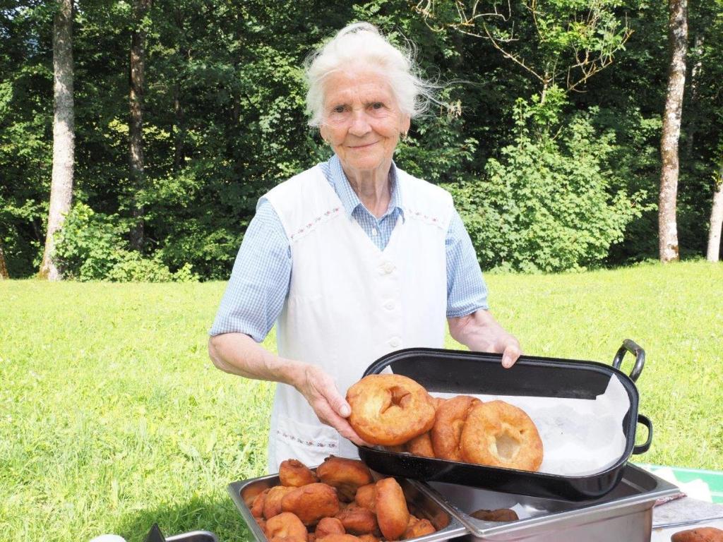 an older woman holding a tray of donuts at Erlachmühle in Mondsee