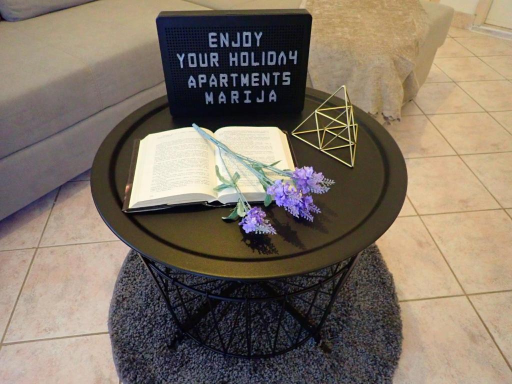 a table with a book and flowers on it at Apartments Marija in Karlobag