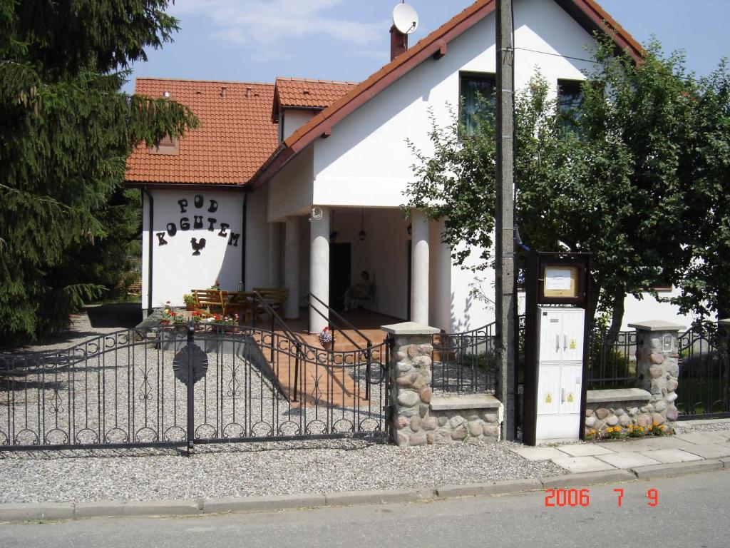 a white house with a gate in front of it at Pod Kogutem in Piecki