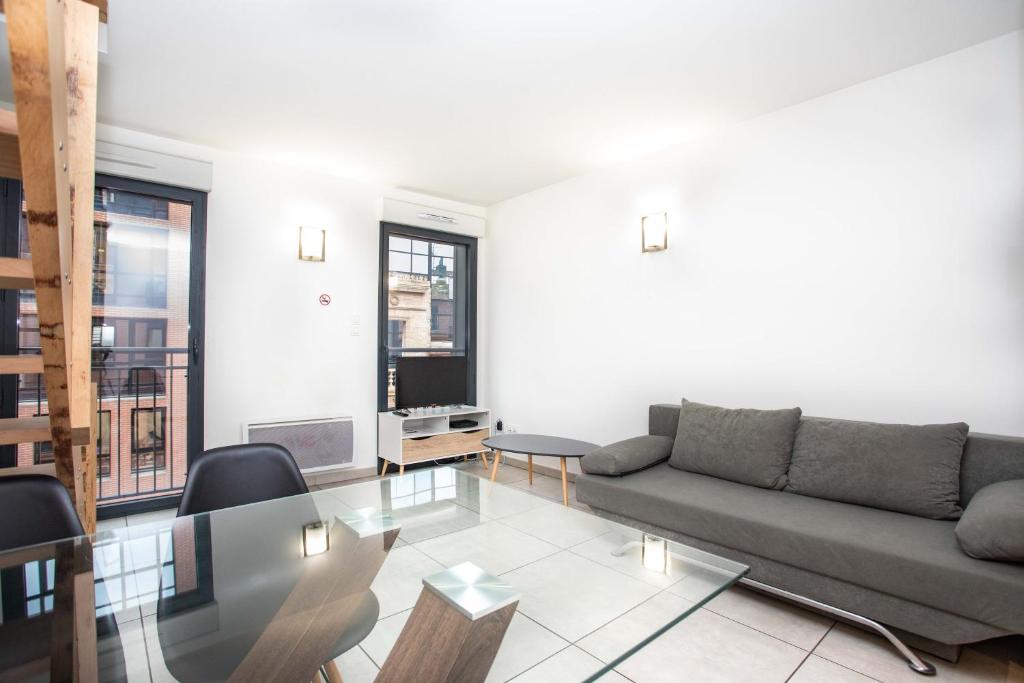 uma sala de estar com um sofá e uma mesa de vidro em 202 - Appartement Duplex Moderne - Jeanne d'Arc, Toulouse em Toulouse