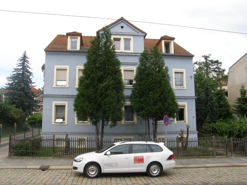 un coche blanco estacionado frente a una casa azul en Apartment-Ferienwohnung Dresden-Briesnitz, en Dresden