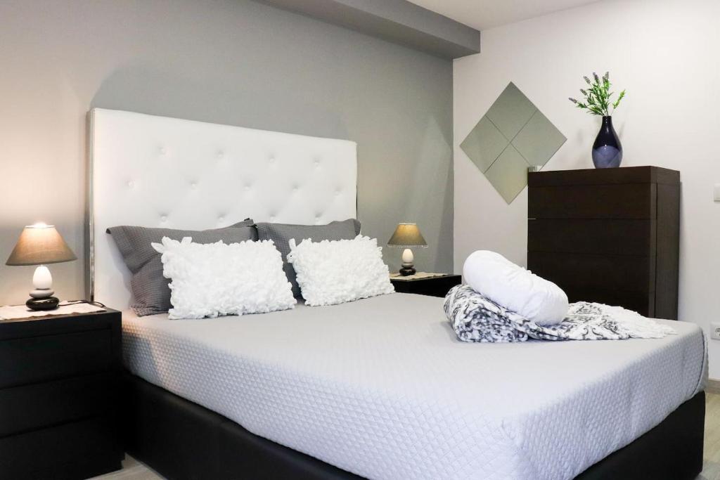 um quarto com uma cama grande com lençóis brancos e almofadas em Casa Nossominho em Vila Nova de Cerveira