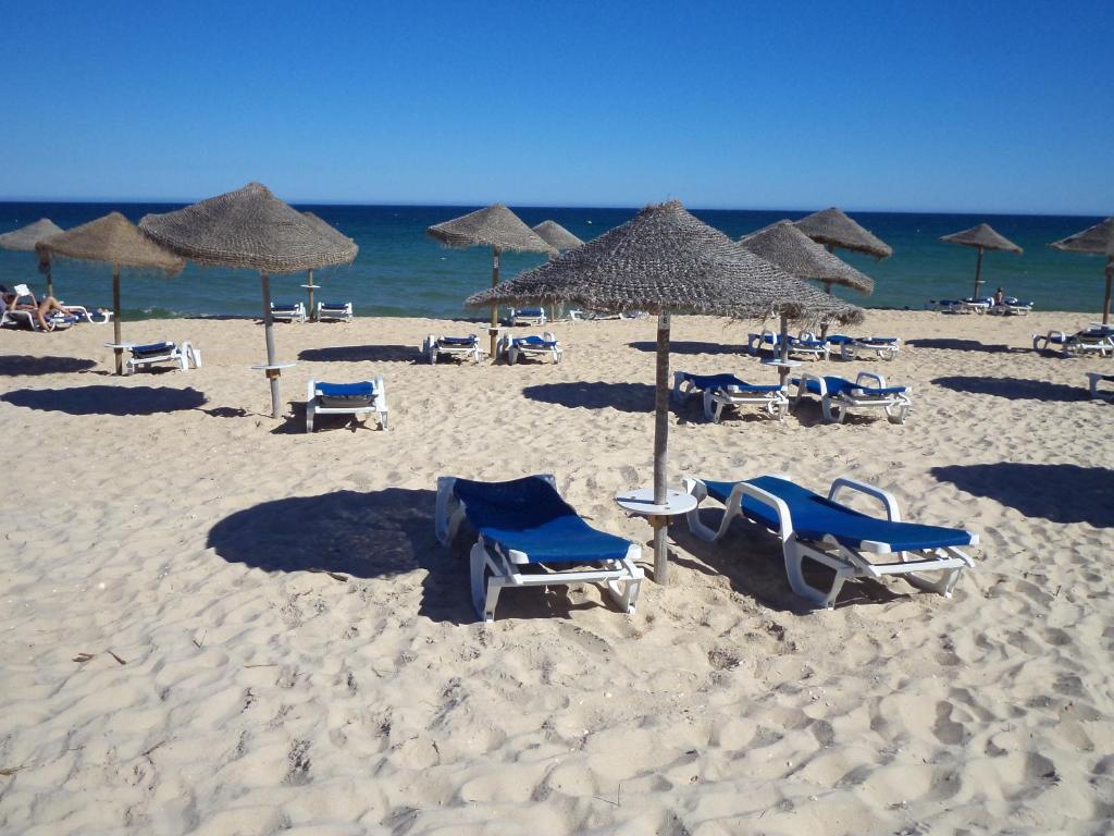 a group of chairs and umbrellas on a beach at Penthouse Ria in Santa Luzia