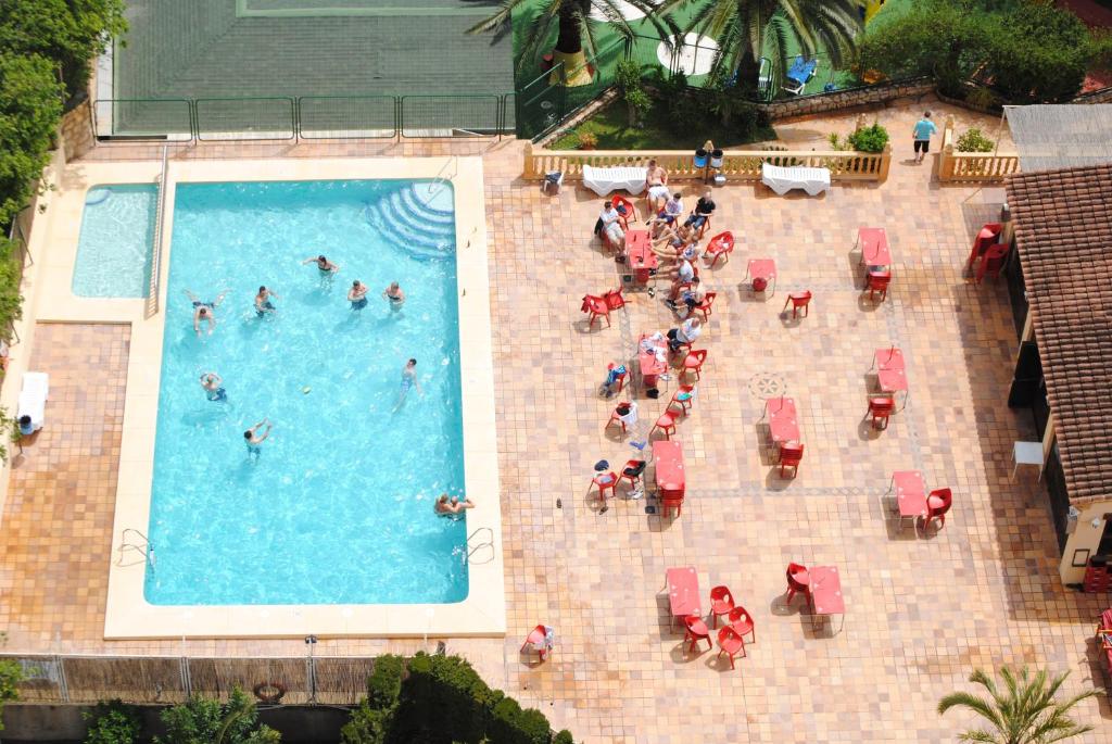 un grupo de personas sentadas alrededor de una piscina en Apartamentos Palm Court, en Benidorm
