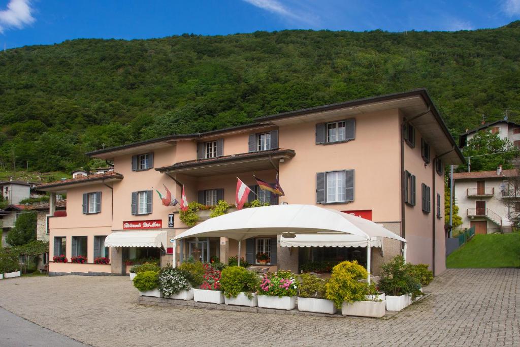 ein großes rosa Gebäude mit einem Regenschirm davor in der Unterkunft Hotel Del Mera in Sorico