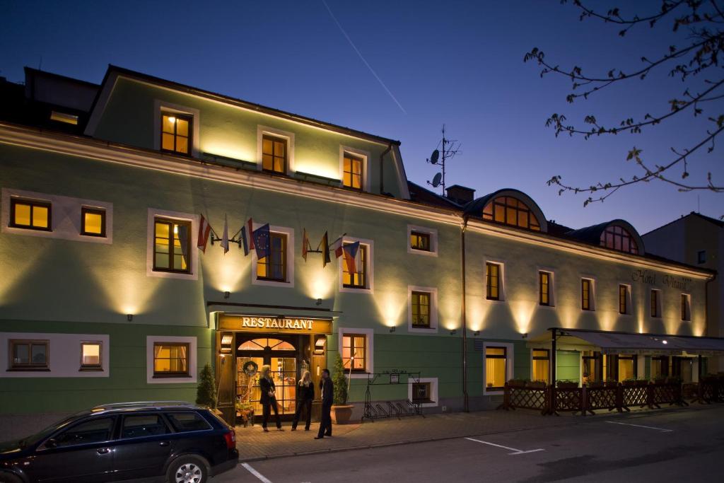 a large green building with people standing outside of it at Hotel Vltava in Frymburk