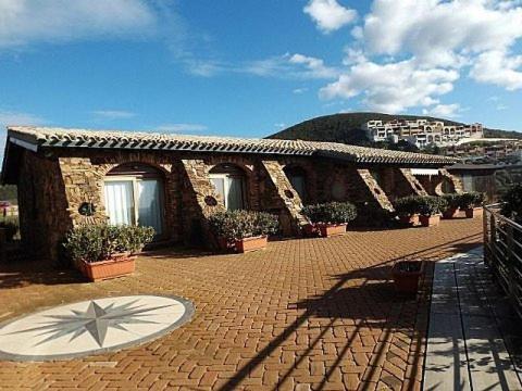 a building with potted plants on a brick patio at Hotel Corsaro Nero in Portu Maga