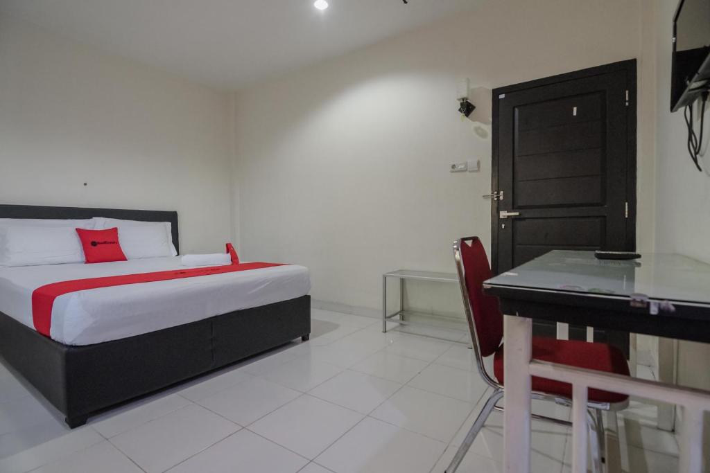a bedroom with a bed and a desk in it at RedDoorz Syariah near Jamtos Jambi in Jambi