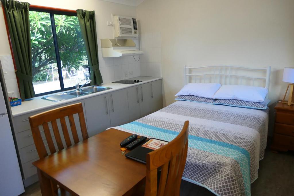 1 dormitorio con cama, mesa y lavamanos en Mt Isa City Motel, en Mount Isa