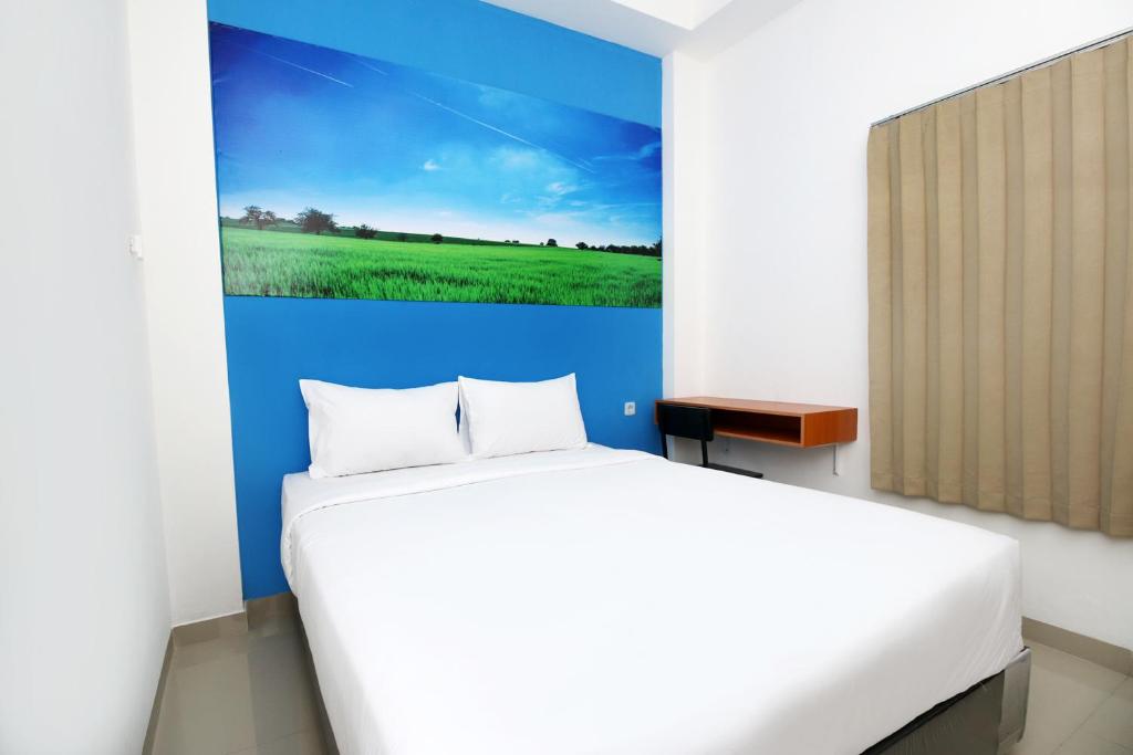a bedroom with a white bed and a painting on the wall at Polamas Residence Padang in Padang
