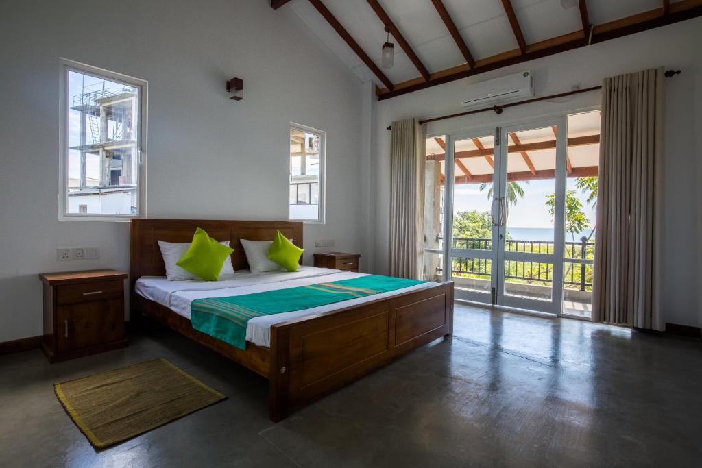 a bedroom with a bed with green pillows at Blue Sands Beach Resort in Pasikuda