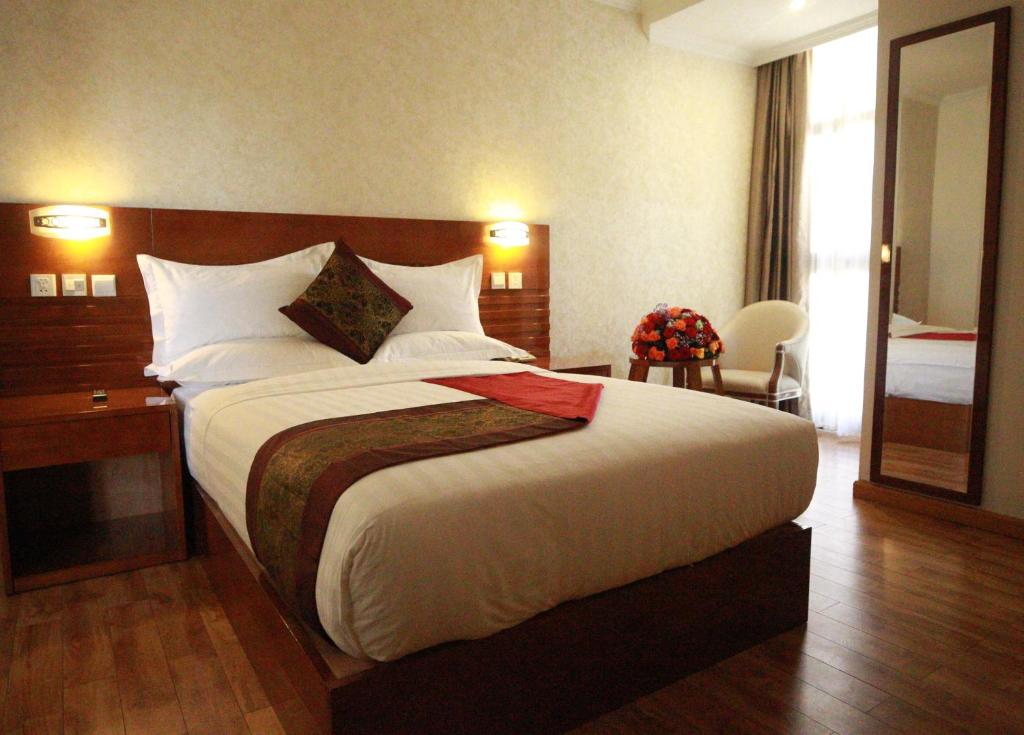 a hotel room with a large bed and a mirror at Marcen Addis Hotel in Addis Ababa