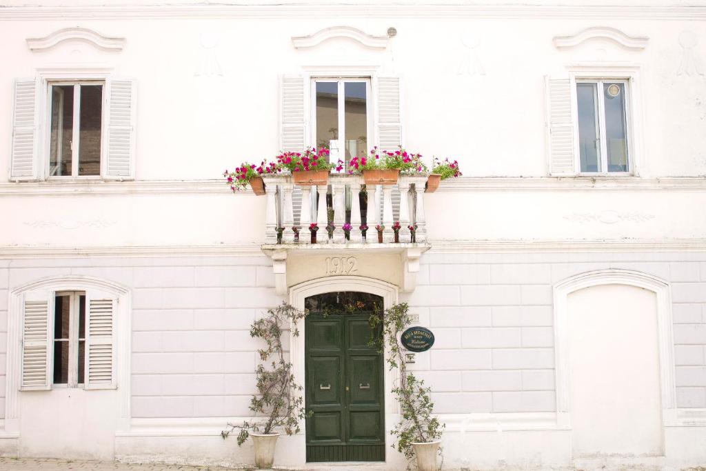 a white building with a green door and a balcony with flowers at Bed&Breakfast 1912 in Fermo