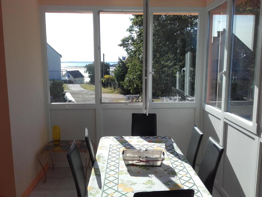 comedor con mesa y 2 ventanas en Au calme, les pieds dans l'eau, 106 Route de la Pointe de Ruault 56370 SARZEAU, en Sarzeau