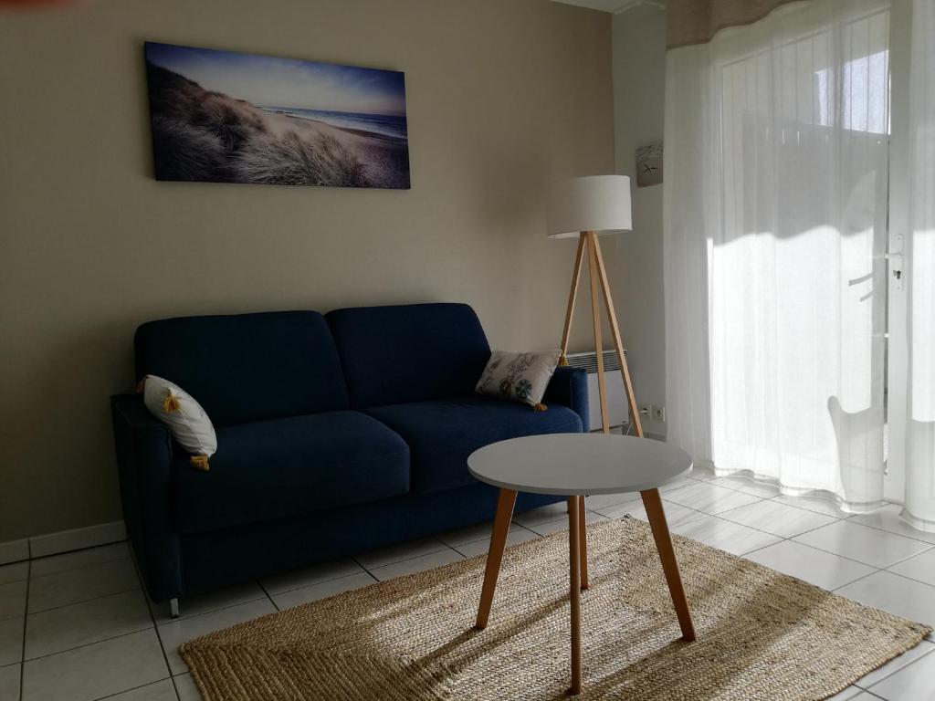 un salon avec un canapé bleu et une table dans l'établissement Appartement la Rochelle, à Aytré