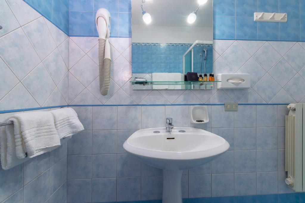 W wyłożonej niebieskimi kafelkami łazience znajduje się umywalka i lustro. w obiekcie CDH Hotel Modena w mieście Modena