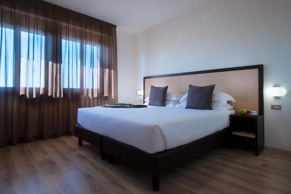 a bedroom with a large bed and a large window at CDH Hotel Modena in Modena