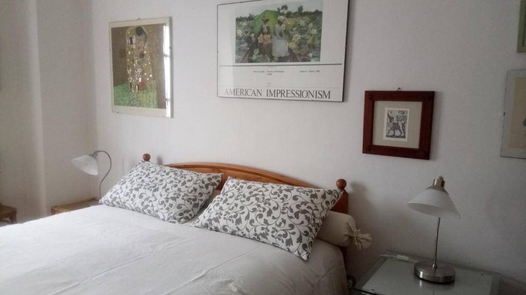 ein Schlafzimmer mit einem Bett und einer Lampe und Bildern an der Wand in der Unterkunft CASA BARTOLACCI COZY APARTMENT (NEAR FLORENCE CITY CENTER) in Bivigliano