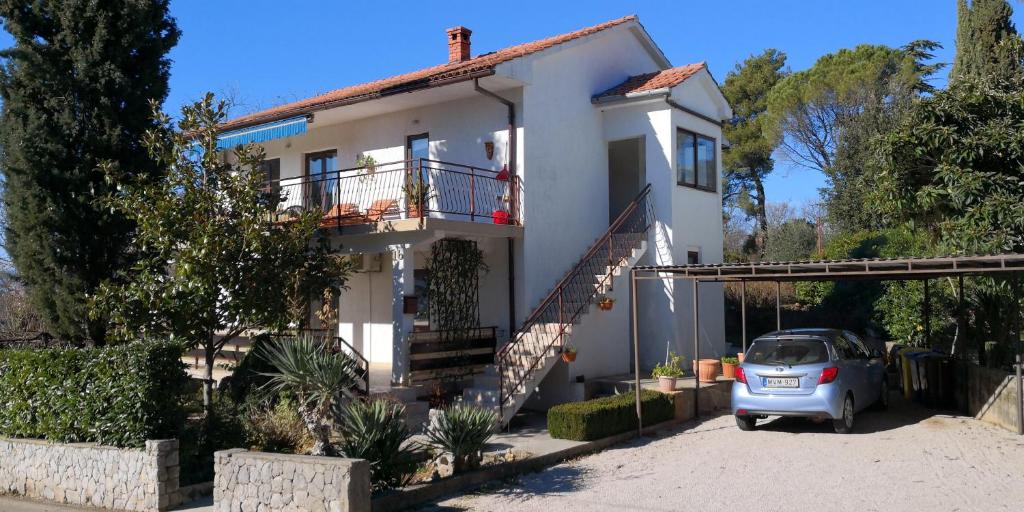 a white house with a car parked in front of it at Apartmans Luce e Stella in Malinska