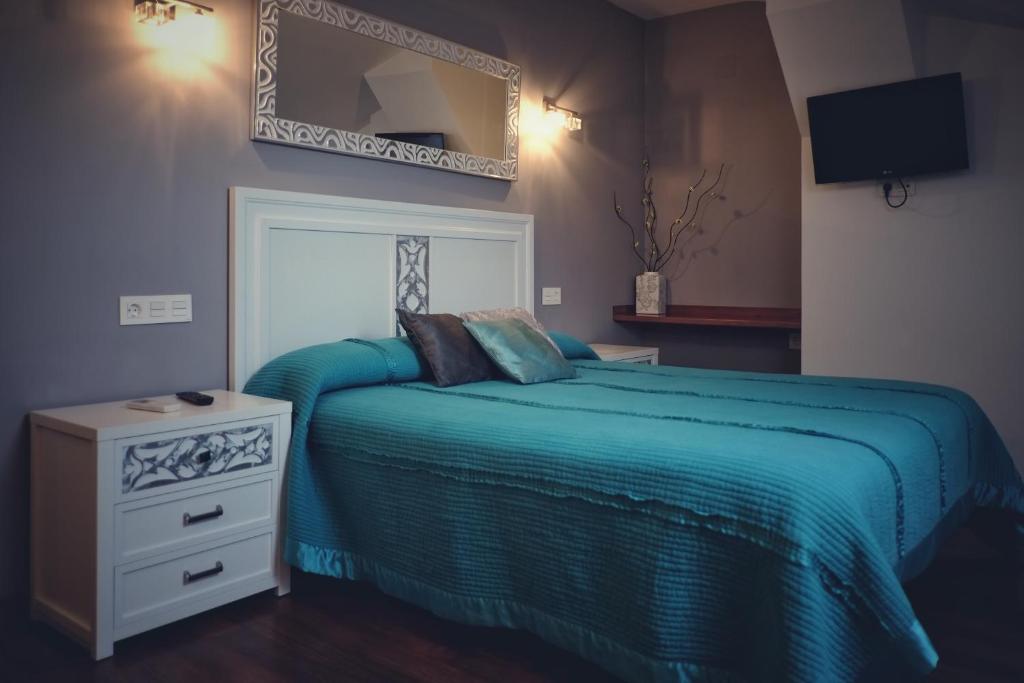 um quarto com uma cama azul e um espelho em La Juderia de Las Arribes em Vilvestre